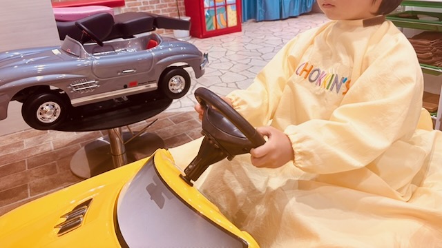 黄色の車に乗って楽しそうにカット中の4歳