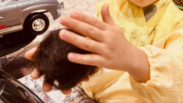 チョッキンズで集めた髪の毛を手に持つ4歳の子ども