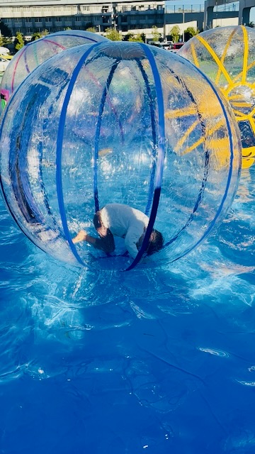 水上で転がれる巨大バルーンで遊ぶ子ども